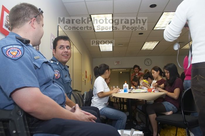 Officers Wesley Schlather and Joshua Martin observe students decorating masks at a domestic violence expressive arts workshop for survivors and friends of survivors of domestic and relationship violence.

Filename: SRM_20061023_1732064.jpg
Aperture: f/5.6
Shutter Speed: 1/100
Body: Canon EOS 20D
Lens: Canon EF-S 18-55mm f/3.5-5.6