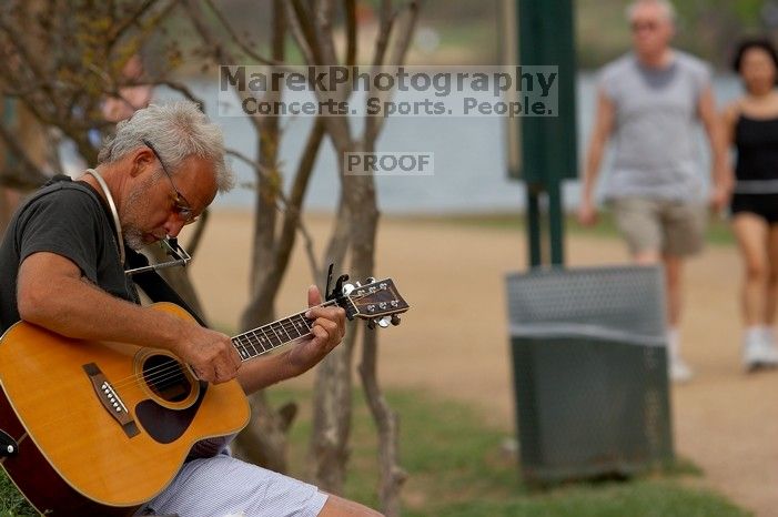 Woode Wood playing his acoustic guitar at Town Lake Hike & Bike trail in Austin, TX.

Filename: SRM_20060312_094536_3.jpg
Aperture: f/4.0
Shutter Speed: 1/1000
Body: Canon EOS 20D
Lens: Canon EF 80-200mm f/2.8 L